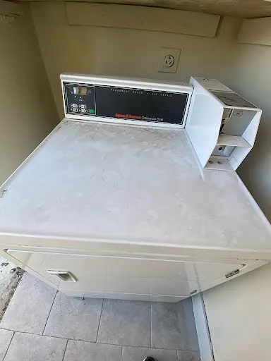 Commercial coin-operated top-load washer in a laundry room serviced in Las Vegas
