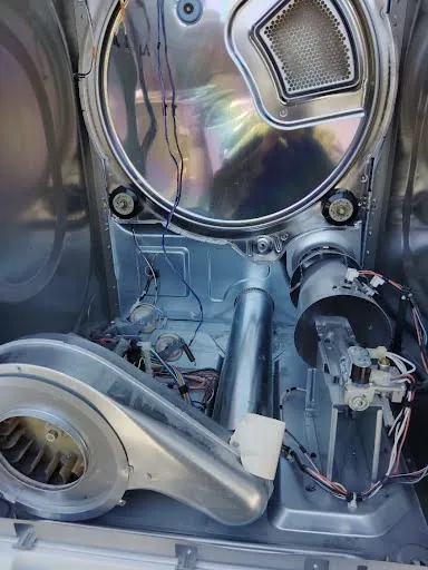 Clothes dryer with the front panel removed showing the drum, blower housing and motor