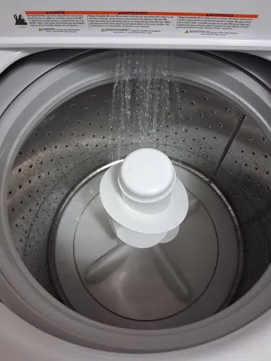 Top-load washing machine filling with water during a test cycle after repair